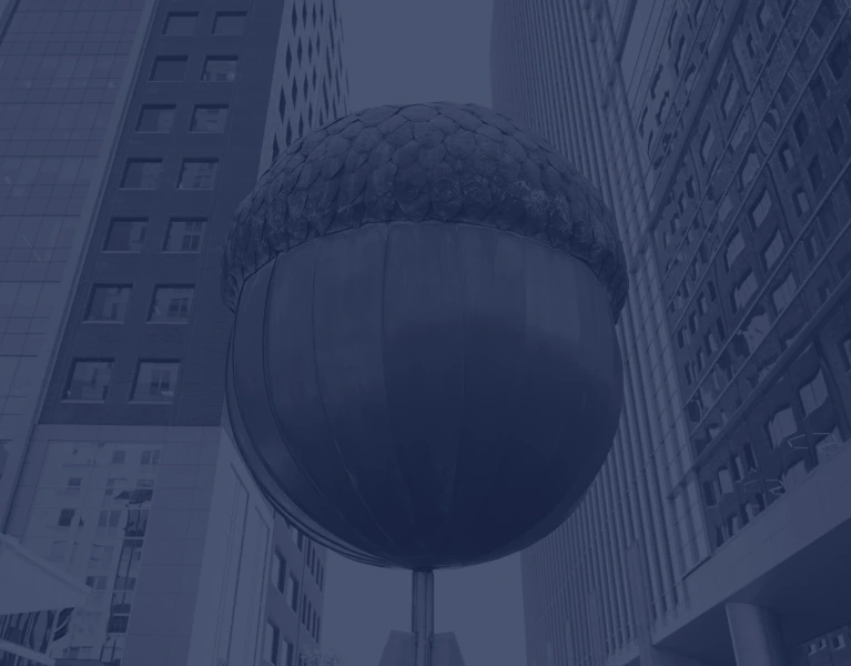 a large acorn sculpture in front of tall buildings