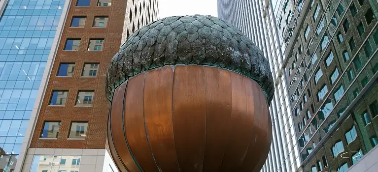 a large bronze acorn statue in front of a tall building