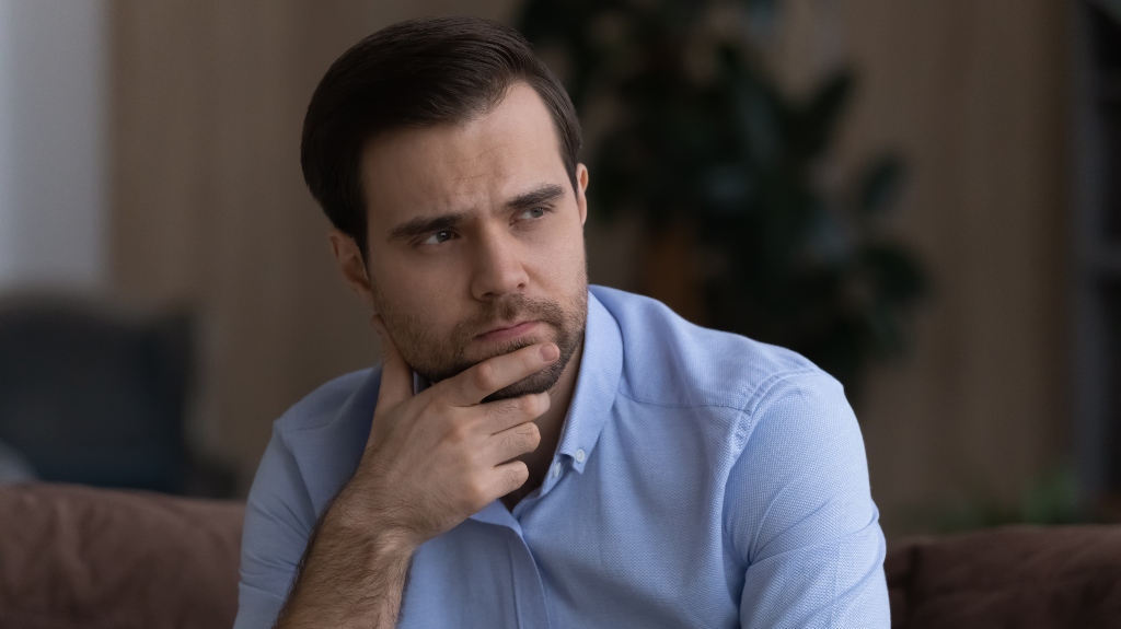 unhappy upset young man sit on couch