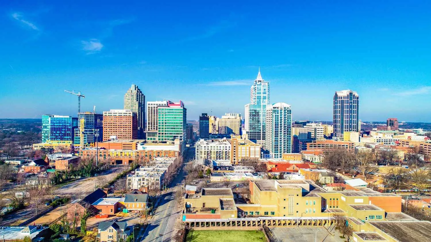 Aerial view of a vibrant downtown skyline with modern skyscrapers against a clear blue sky, showcasing urban development and city life.