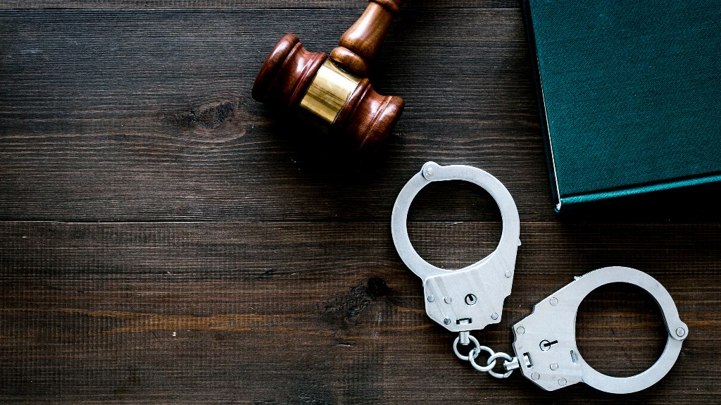 Metal handcuffs near judge gavel and law book