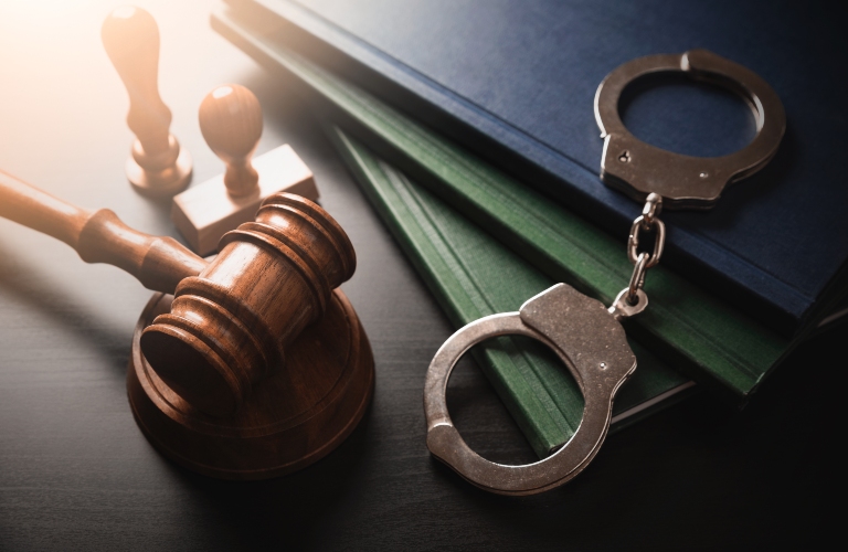 Handcuffs and wooden gavel are on the table